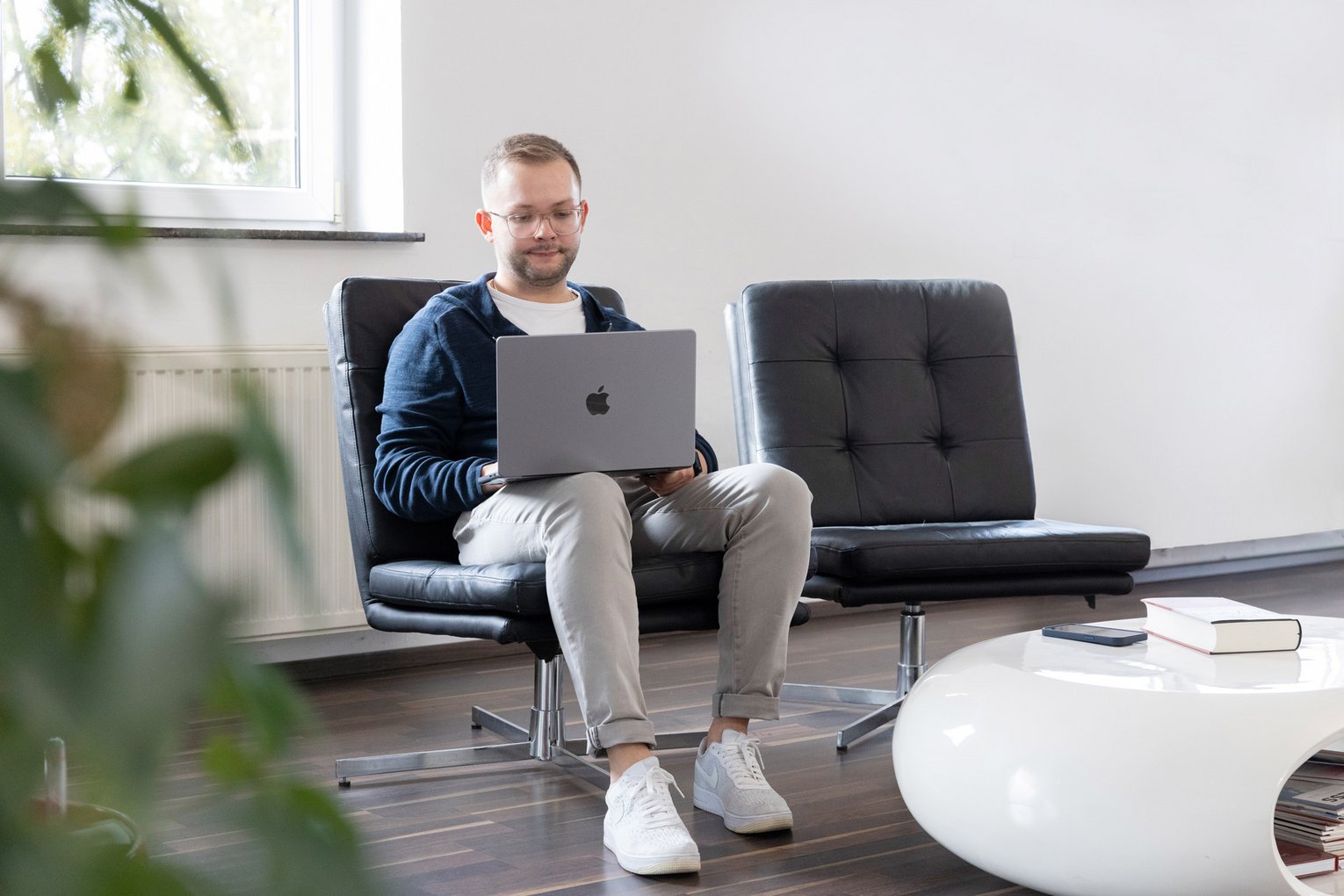 arcworx E-Commerce Mitarbeiter mit Laptop in einer Lounge mit Designmöbeln